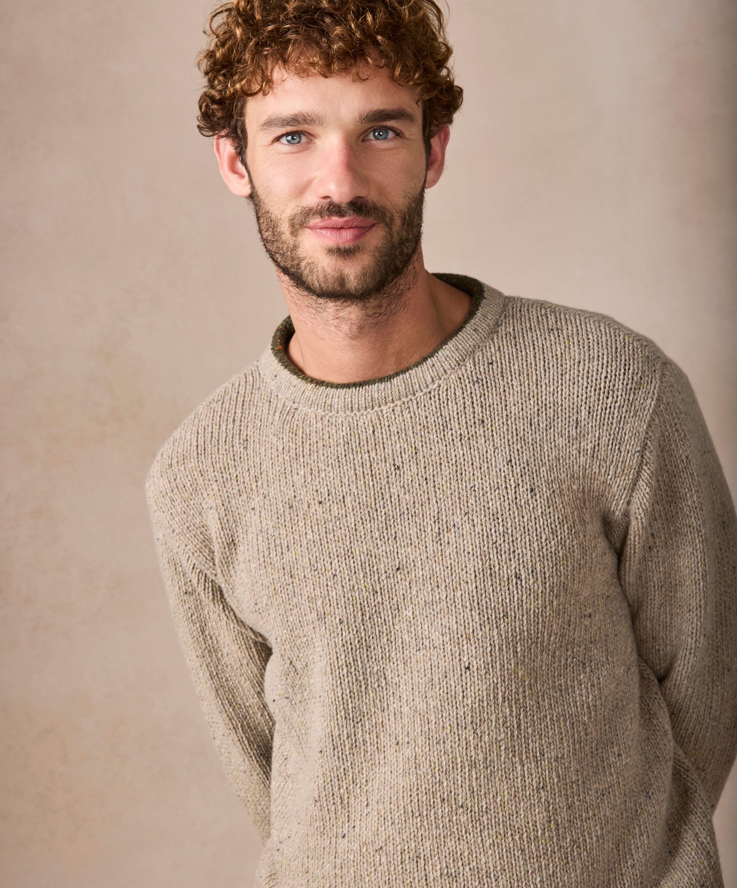 Man wearing a beige sweater against a plain background