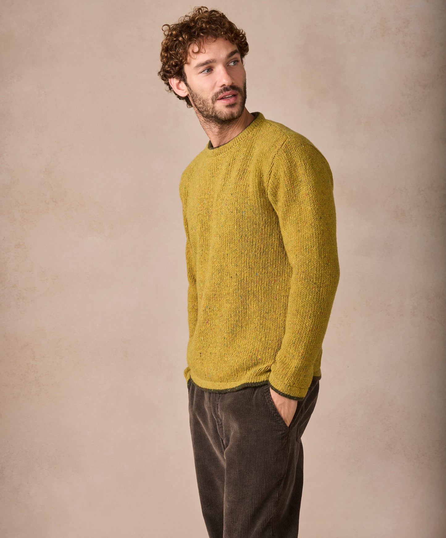 Man wearing a mustard yellow sweater against a beige background