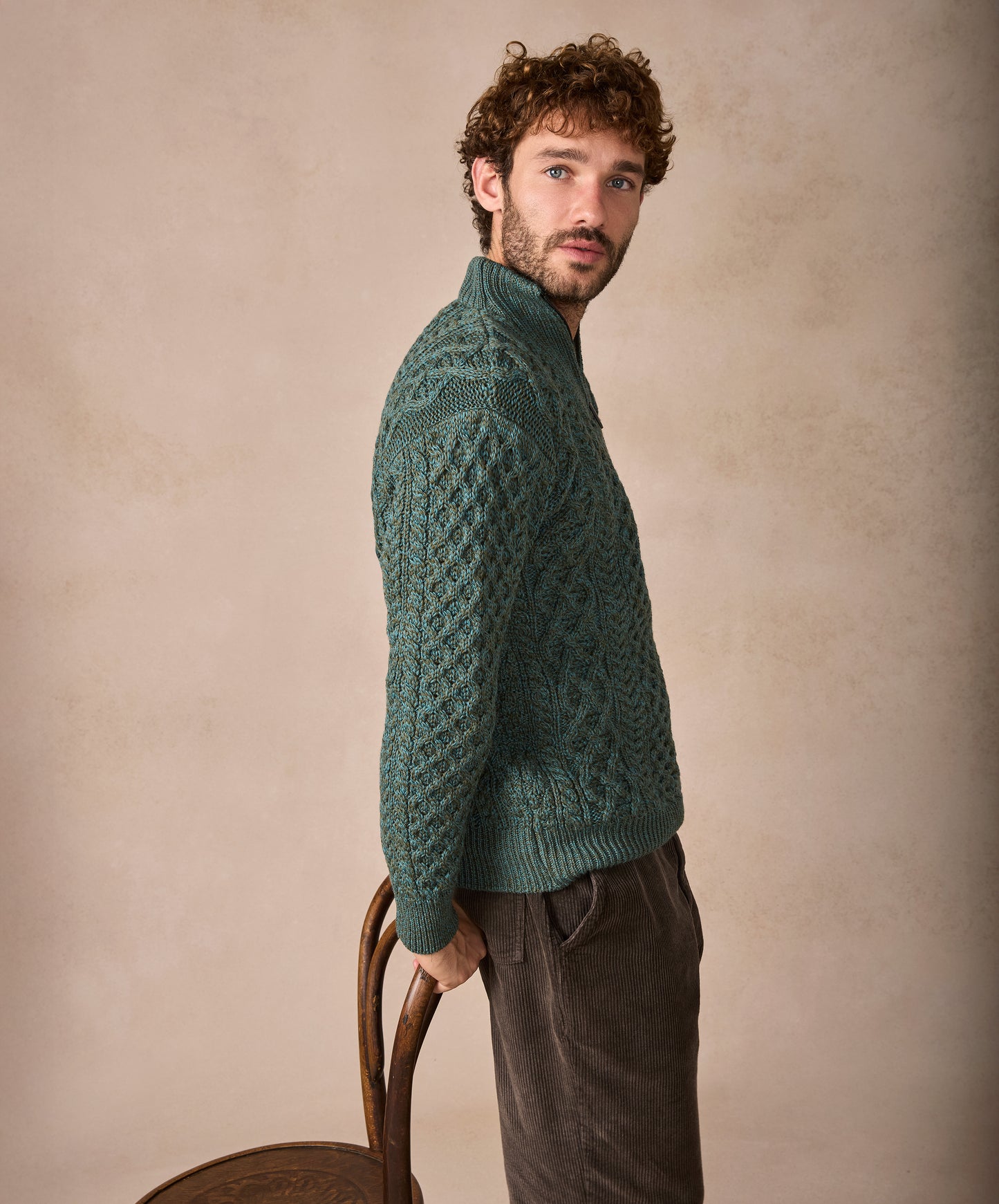 Man wearing a green knitted sweater against a beige background