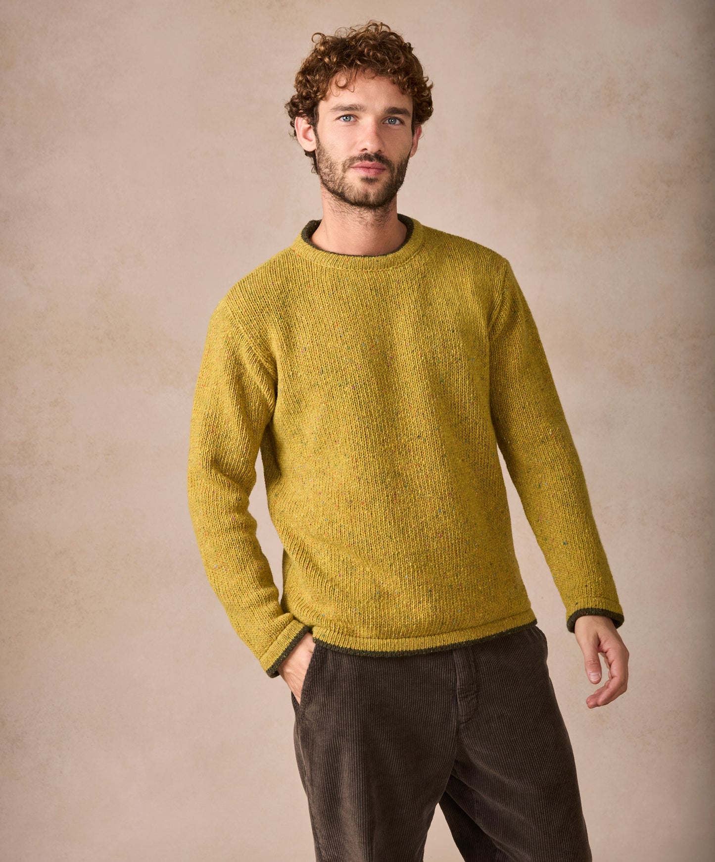 Man wearing a mustard yellow sweater against a beige background