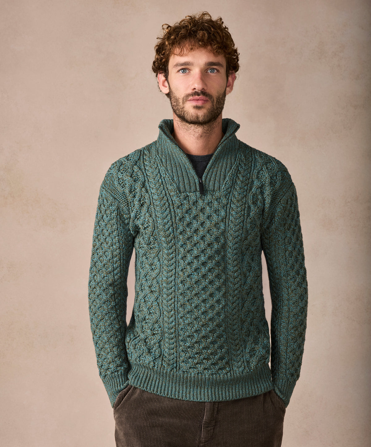 Man wearing a green patterned sweater against a beige background