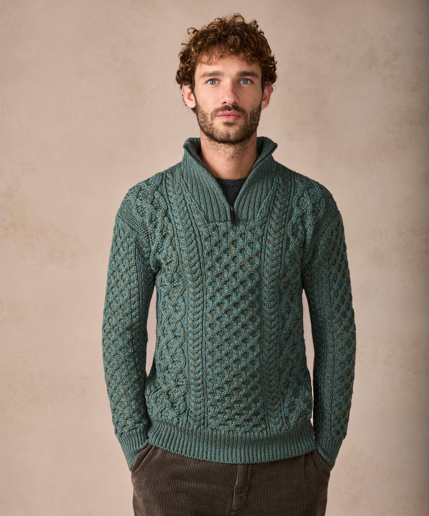 Man wearing a green patterned sweater against a beige background