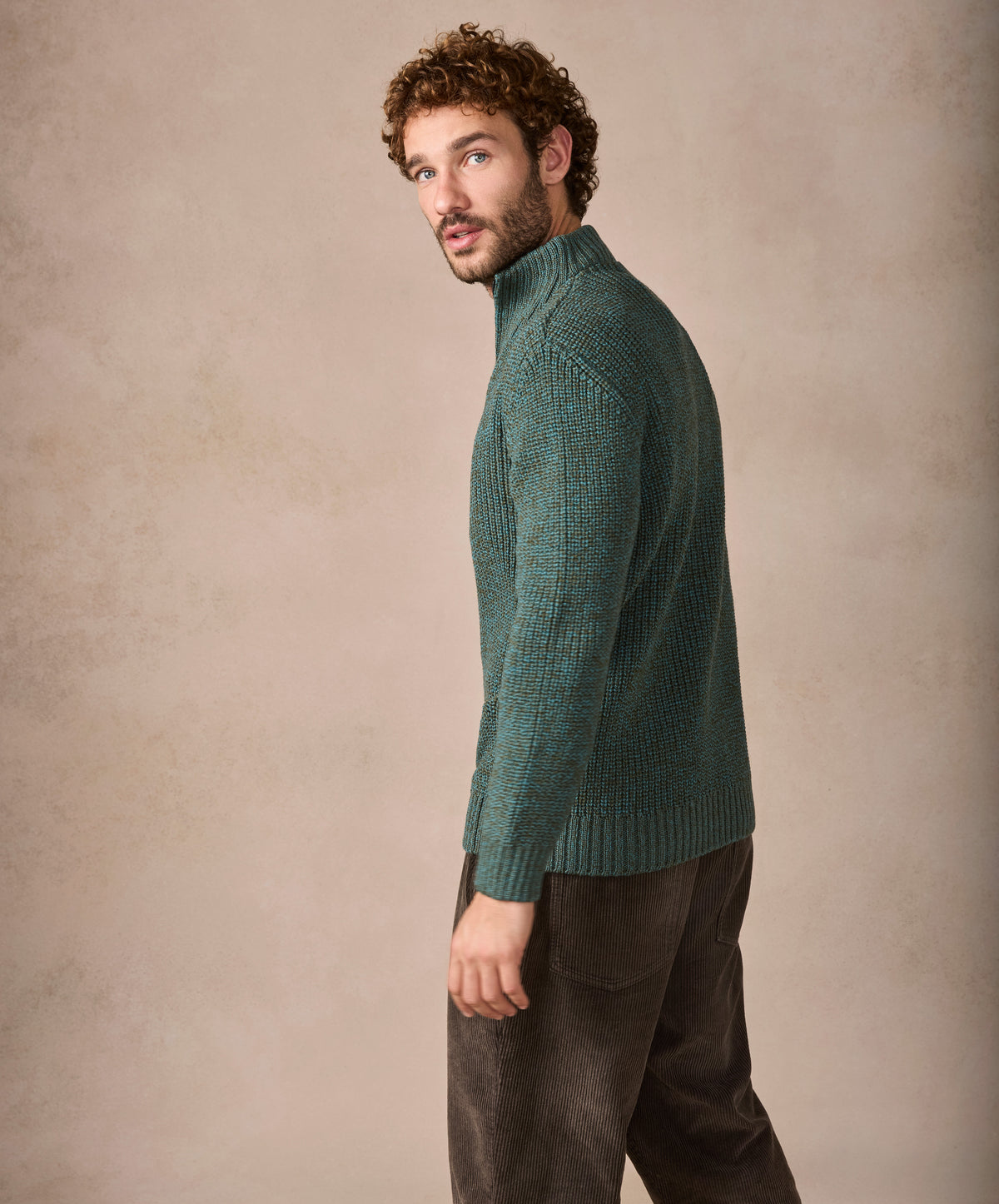 Man wearing a green knitted sweater against a beige background
