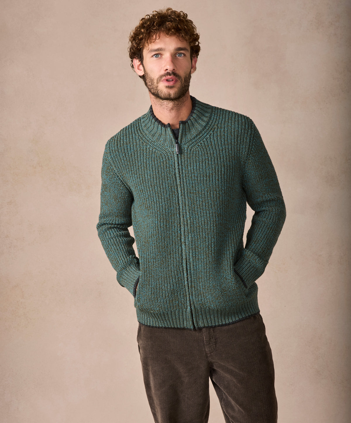 Man wearing a green knitted sweater against a beige background