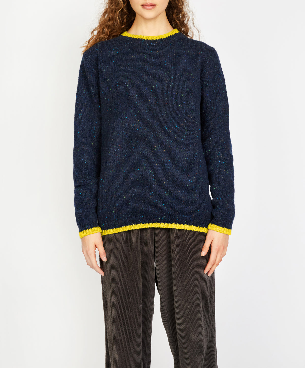 Person wearing a navy sweater with yellow trim on a white background
