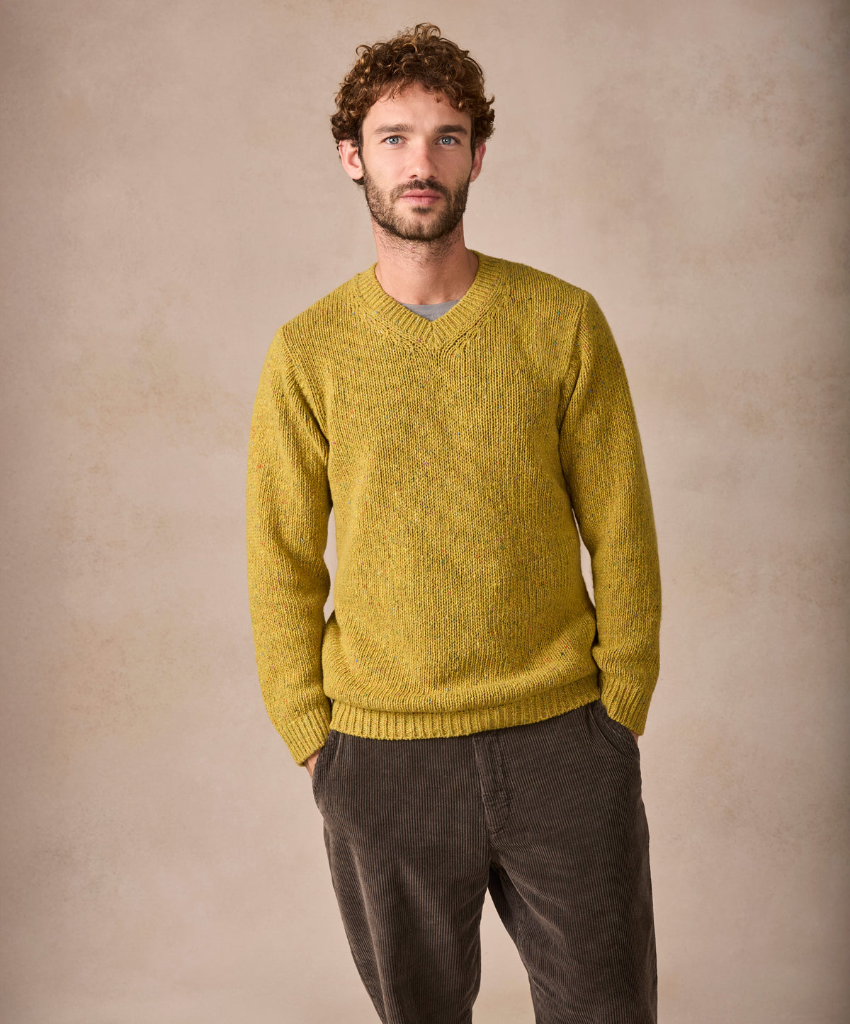 Man wearing a mustard yellow sweater against a beige background